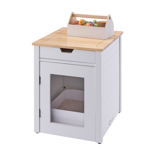 A modern white and wood-toned cat litter box enclosure with a clear front door is shown, featuring a storage drawer above the litter compartment. A wooden caddy holding pet toys sits on top of the enclosure.