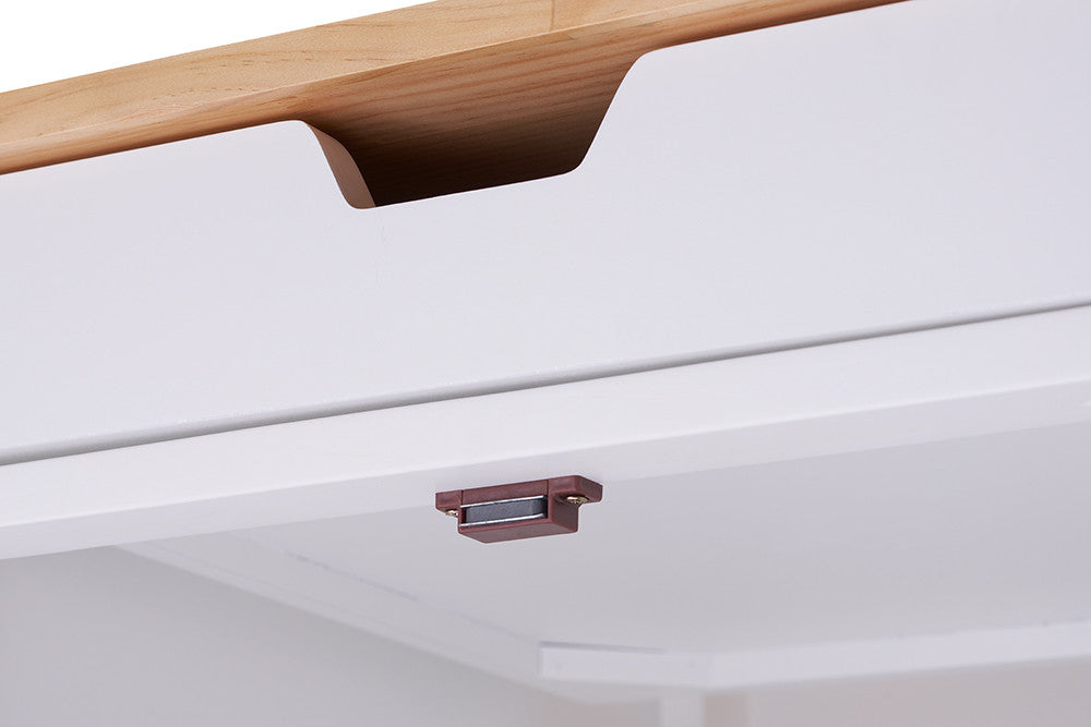 A close-up shot of a white drawer with a brown magnetic catch on the underside of the top panel. The drawer features a cutout handle and is partially open, revealing a glimpse of the interior.