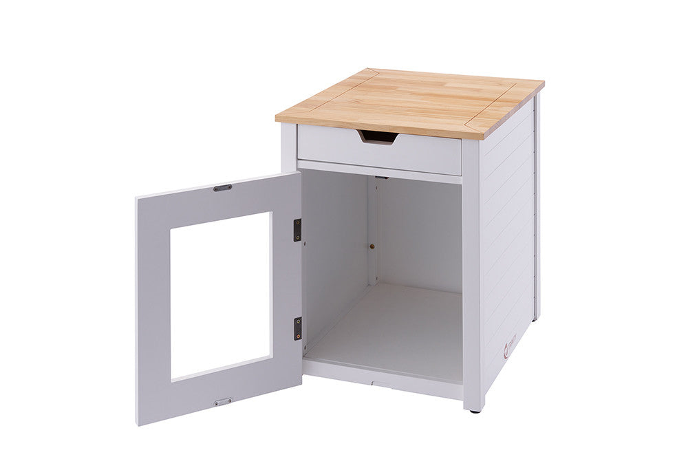 A white wooden cat litter box enclosure with a light wood top is shown with its door open. The enclosure has a drawer above the door and a cutout in the door.