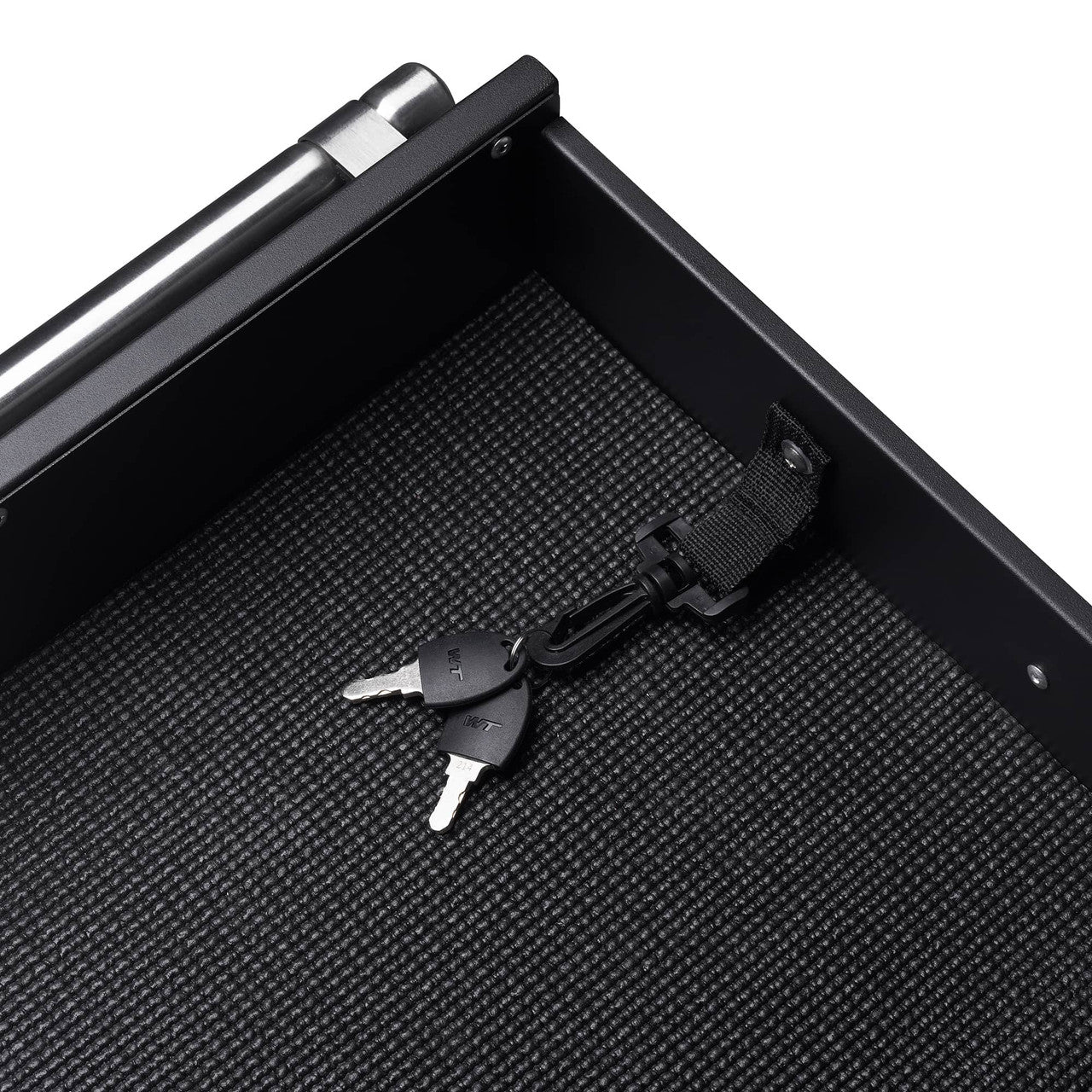 A top-down, close-up shot shows the interior of a black safe. Two silver keys attached to a black lanyard with a velcro strap rest on the safe's textured black bottom.