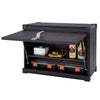 A black Trinity Pro Garage Wall Cabinet is shown with its hinged door open, revealing two shelves containing various items. The top shelf holds a white box, safety goggles on a yellow cloth, and two bottles, while the bottom shelf contains two black and orange storage boxes.