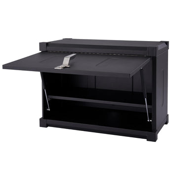 A black Trinity PRO garage wall cabinet is shown with its door partially open, revealing a single shelf inside. The cabinet features a silver latch on the door and gas struts supporting the open position.