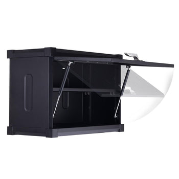 A close-up shot shows a black Trinity PRO garage cabinet with its top door partially open. Two silver gas struts support the open door, which is shown in a motion blur to indicate its upward swing.
