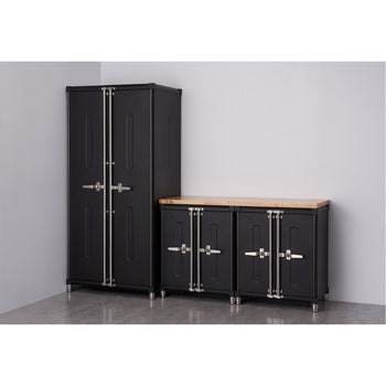 A set of four black Trinity PRO garage cabinets with silver handles and accents is arranged against a light gray wall and floor. The set includes a tall, narrow cabinet with two doors and a workbench-style unit with a light-colored wooden top and two cabinets below.