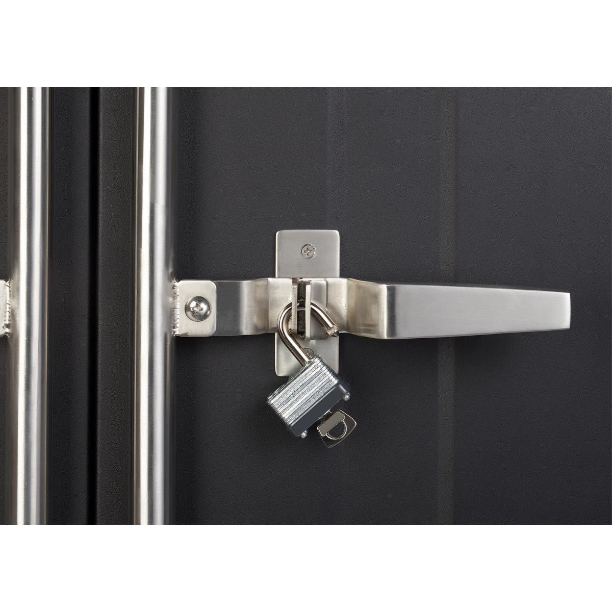 A close-up shows a silver padlock with keys hanging from the latch of a black cabinet or drawer. The latch has a long, horizontal silver handle and is attached to the dark surface with silver hardware.