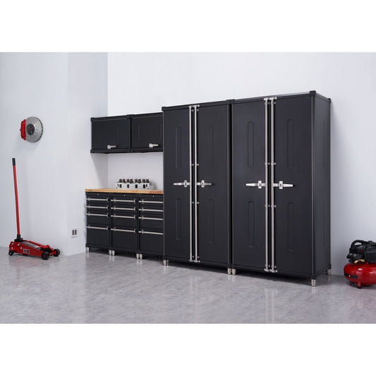 A well-organized garage setup features a Trinity PRO 8-Piece Garage Cabinet Drawer Set in black consisting of 2 locker cabinets 2 wall cabinets, 3 base cabinets with drawers, a 56 inches wide wood top. Various garage items, including a red floor jack, a brake rotor, and a red air compressor, are also visible in the spacious, light-grey floored area.