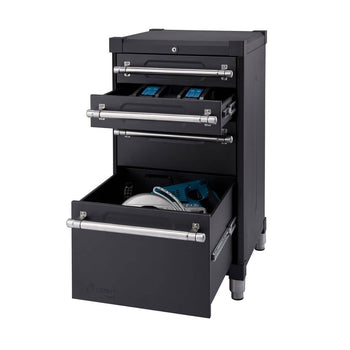 This is a close-up studio shot of a black Trinity Pro Garage Base Cabinet with three drawers. The top two drawers are partially open, revealing blue tool organizers, while the bottom drawer is more open, showing a circular saw and a drill inside.