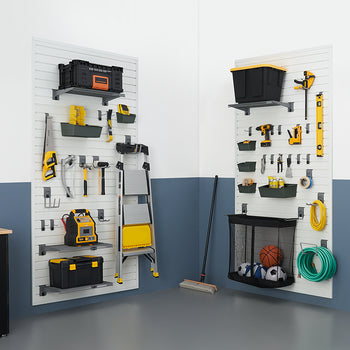A well-organized garage features two wall-mounted slatwall storage systems with various tools and equipment neatly hung and stored. On the left panel, a black cabinet is visible, while a broom and sports equipment in a mesh bag are seen on the right.