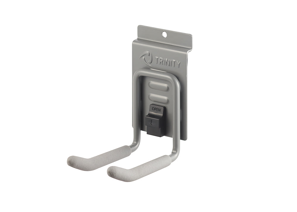 A close-up of a Trinity brand gray metal J-hook, designed for wall mounting. The hook has two foam-padded arms for hanging items, with a black clip in the center marked "OPEN".