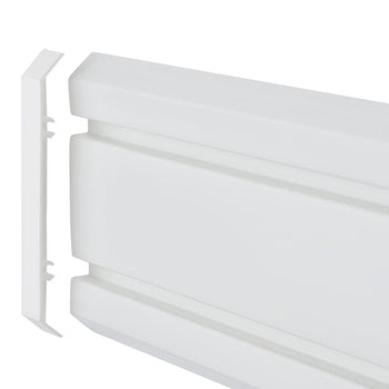 A detailed, eye-level close-up of a white plastic skirting board section. A removable end cap piece is shown detached from the main length, revealing the interlocking clips and a hollow channel for running cables.