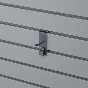 A close-up shot shows a gray slatwall panel with a dark gray security hook attached. The hook has a small 