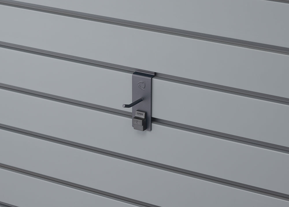 A close-up shot shows a gray slatwall panel with a dark gray security hook attached. The hook has a small "OPEN" label on its lower portion, indicating a locking mechanism.
