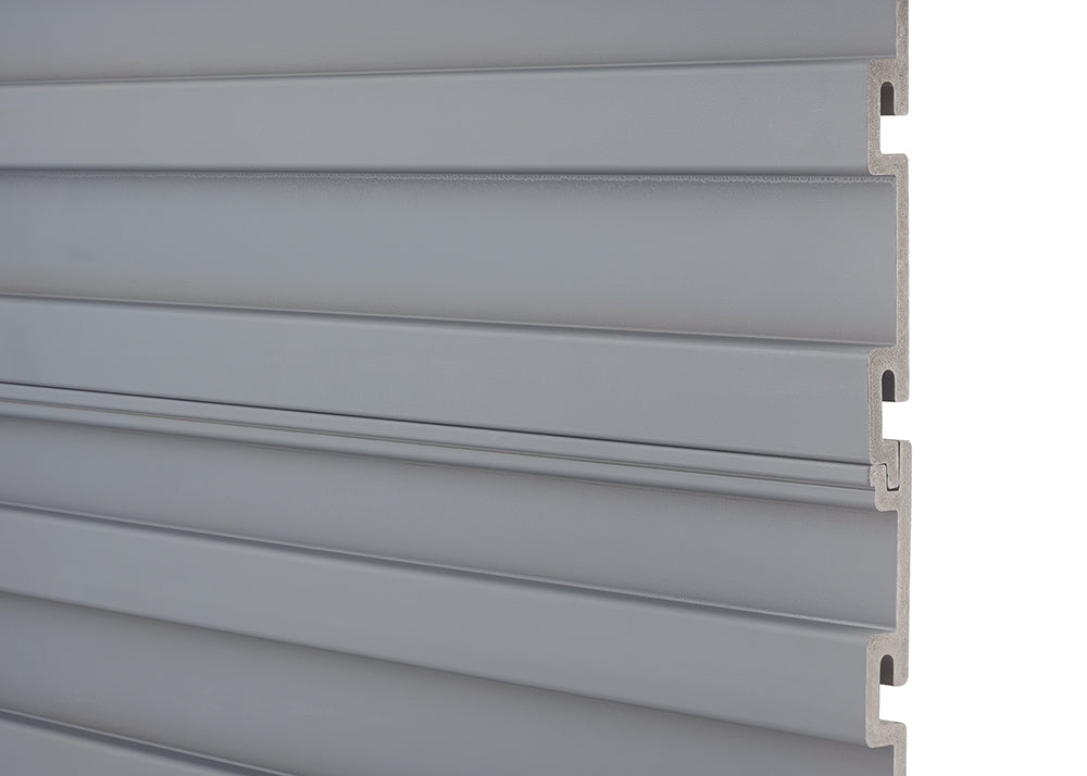 A close-up shot shows several horizontally stacked, light gray slatwall panels. The panels interlock with a tongue and groove system visible on the right edge.