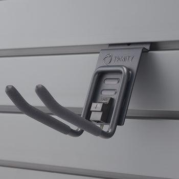 A close-up shot shows a gray double-prong hook with foam padding on the prongs, hanging from a gray slatwall panel. The hook has 