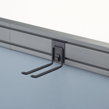 A black metal double hook hangs from a gray wall-mounted track system. The hook is designed to hold two items, with the ends of the hooks curving slightly upward.