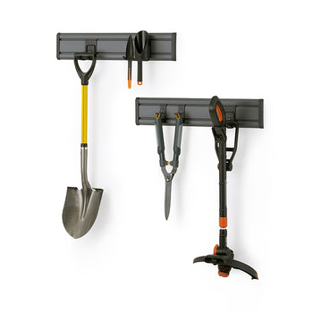 A gray wall-mounted track system holds various gardening tools against a white background. On the top track, a small shovel and hand trowel are hung, while the bottom track displays a large shovel, hedge shears, and a grass trimmer.