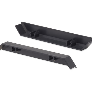 A low-angle shot shows two matte black plastic pieces for a computer keyboard. One piece is a long, thin, rectangular bar, and the other is a wider, trough-like piece, both featuring small rectangular cutouts on their underside.