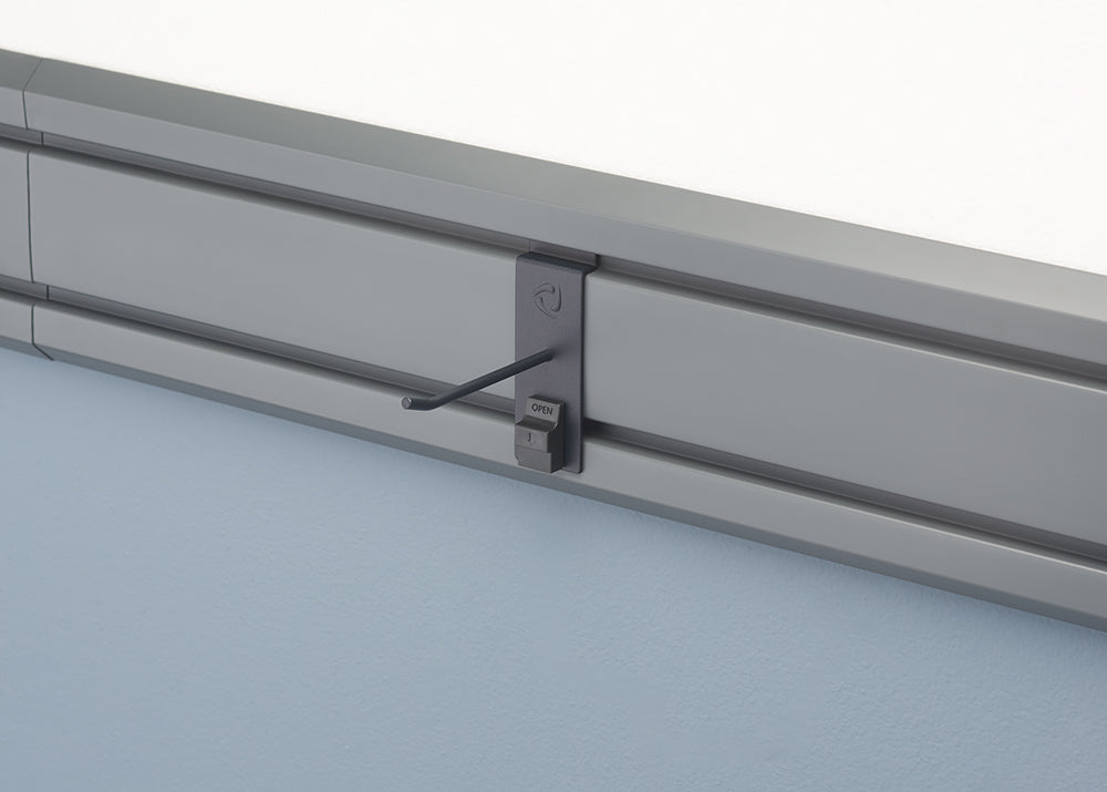 A close-up of a gray wall-mounted rail system. A dark gray accessory with an angled hook is attached to the rail.