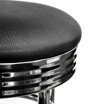 A close-up view shows the black, cushioned seat and the shiny, chrome base of a Trinity 30