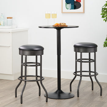A small, black pub-style table with a round top stands between two matching tall bar stools. The stools have black faux leather seats and distressed black metal frames with curved legs.