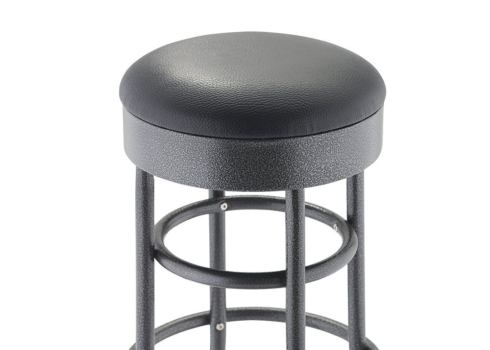 A close-up of the top of a bar or counter stool shows a round, padded seat covered in black textured faux leather. The seat rests on a black, speckled metal base with tubular legs and footrings.