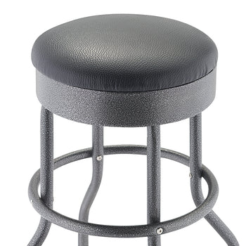 A close-up view of a bar stool with a round, black faux-leather cushioned seat and a textured, metallic black finish on the metal base and legs. The stool's base is made of curved metal tubing and features a circular footrest ring.