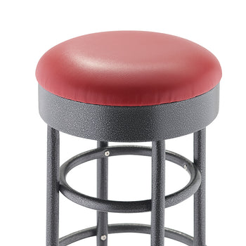 A close-up shot focuses on the seat of a round bar stool with a dark red, cushioned top. The base is a black, textured metal with visible circular supports and legs.