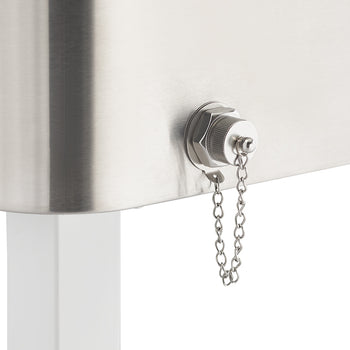A close-up shot of a stainless steel container shows a silver drain plug with a chained cap on its side. The container sits atop a white leg, against a plain white background.