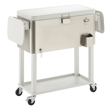 A rectangular, brushed stainless steel cooler with a white lid sits on a white metal cart with wheels. The cooler has an attached bottle opener, a small side caddy, and two fold-out white side tables.