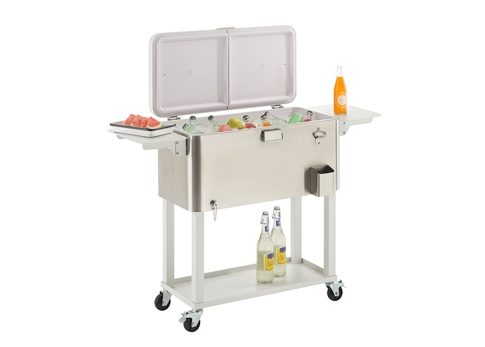 A stainless steel outdoor cooler on wheels with its lid open, revealing a variety of drinks on ice. The cooler has two side tables, one holding a plate of watermelon slices and the other an orange soda bottle, with two more bottled drinks on a shelf below.