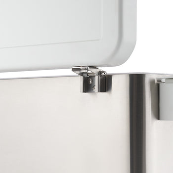 A close-up shot shows a shiny, metallic hinge connecting a white lid to a stainless steel appliance. The hinge is partially visible, with the lid slightly ajar, revealing the mechanical connection.