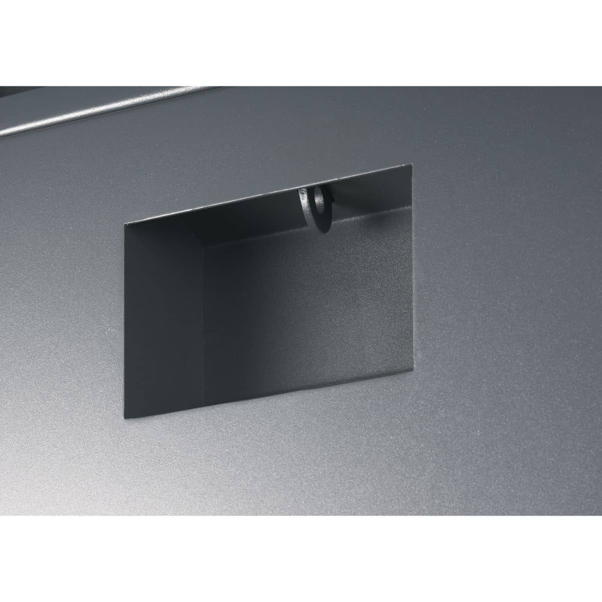 A close-up shot shows a rectangular opening in a smooth, matte gray surface. Inside the opening, the same gray material forms a small, recessed compartment or channel with tamper-proof locking system.