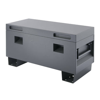 A rectangular, dark grey Trinity job box is shown from a slightly elevated angle. The heavy-duty steel storage box features recessed handles on the lid and sides, and is elevated by two integrated, reinforced feet.