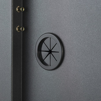 A close-up view highlights a circular rubber cable management grommet built into the back panel of a dark gray steel storage cabinet. The flexible rubber pass-through port allows power cords to pass through cleanly while keeping interior wiring neat and organized.