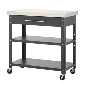 A dark gray rolling kitchen cart with a stainless steel countertop is shown completely empty against a solid white background. It features a top drawer with a silver handle, two lower open storage shelves, and four caster wheels at the base.