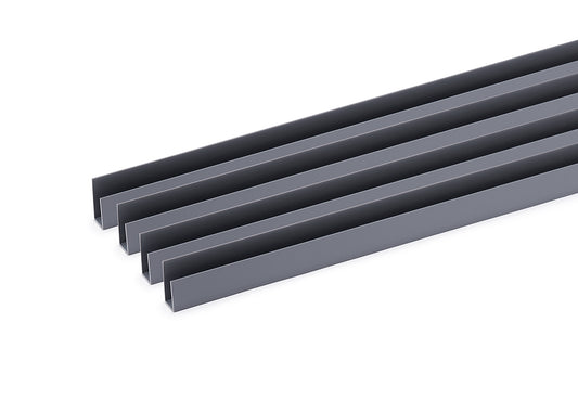 A top-down, slightly angled shot shows four identical, dark gray U-shaped channels lying parallel to each other on a white surface. The channels are uniform in size and color, suggesting they are likely extruded metal or plastic profiles.
