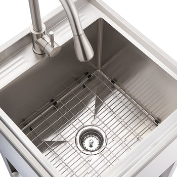 A top-down view shows a clean, modern stainless steel utility sink set into a white surface. It features a brushed stainless steel gooseneck faucet with a single handle, a deep sink basin with a removable bottom grid, and a central basket strainer drain.