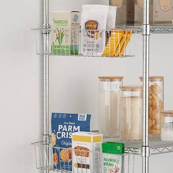 A close-up shot shows two wire metal hanging baskets attached to a chrome shelving unit. The baskets hold various pantry items, including boxes of crackers, a bag of coffee, a container of parmesan cheese, and jars of dry goods.